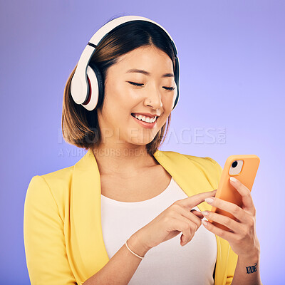 Buy stock photo Headphones, music and happy Asian woman with phone in studio for social media, subscription and radio. Female person on smartphone listening to audio, song and track on purple background to relax