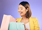 Check, shopping bag and young woman for fashion sale, discount or retail prize on studio, purple background. Excited model, asian person or happy customer with choice, giveaway and wealth or gift