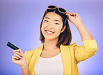 Credit card, shopping portrait and woman in sunglasses, retail banking and finance, e commerce or payment. Happy customer, fashion model or asian person for paperless loan on studio purple background