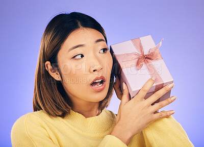 Buy stock photo Thinking, gift and box with face of asian woman in studio for birthday, celebration and curious. Surprise, wow and party with female person and present on purple background for giveaway and package