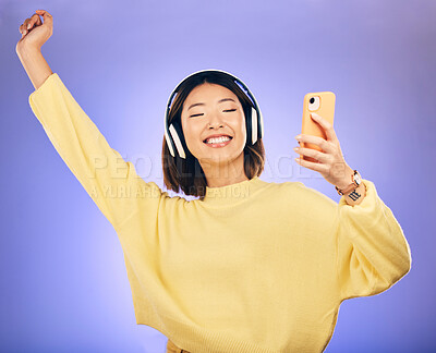 Buy stock photo Dance, music and Asian woman with phone in studio for streaming, subscription and radio. Relax, headphones and happy female person on smartphone listen to audio, song and track on purple background
