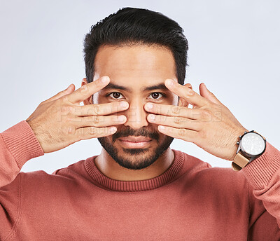Buy stock photo Portrait, eyes and asian man with fingers on face in studio with confidence, personality and persona on grey background. Hands, pose and male person with hand gesture for mask, masquerade or ego