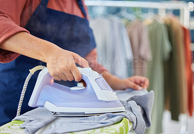 Buy stock photo Closeup of a female maid ironing clothes on a board in the laundry room of a modern house. Cleaning, chores and zoom of a woman cleaner or housewife steaming washing with an iron in an apartment.
