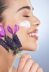 Woman, face with cream and skincare with flower, natural beauty product with lavender or facial cosmetics in studio background. Skin care, moisturiser and purple flowers for organic cosmetic wellness