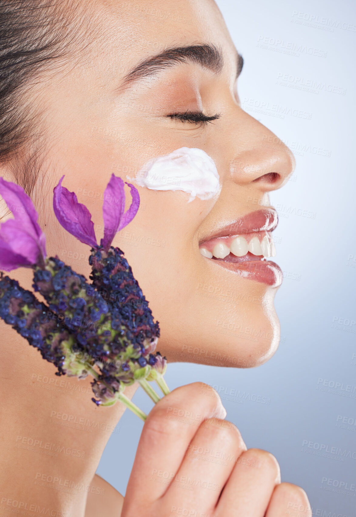 Buy stock photo Woman, face with cream and skincare with flower, natural beauty product with lavender or facial cosmetics in studio background. Skin care, moisturiser and purple flowers for organic cosmetic wellness