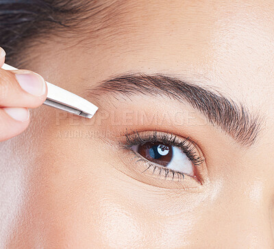 Buy stock photo Closeup of a young woman tweezing her eyebrows in a studio for grooming or hair removal face routine. Skincare, beauty and zoom of female model doing a facial epilation treatment with metal tweezers.