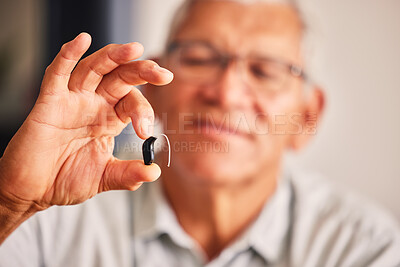 Buy stock photo Hand holding hearing aid, senior man and tech for ears, health and wellness for retirement in nursing home. Elderly person with disability, audio or sound technology to listen in closeup at house