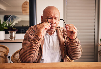 Buy stock photo Glasses, vision and a senior man at a table in the living room of his home during retirement. Thinking, relax and eyesight with an elderly male person holding prescription frame lenses in his house