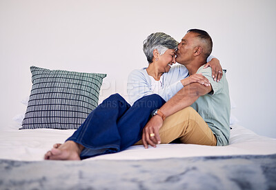 Buy stock photo Love, kiss and senior couple on their bed in their home while relaxing, bonding and spending time together. Happy, affection and elderly man and woman in retirement resting in bedroom in their house.