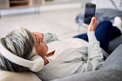 Buy stock photo Senior woman, headphones and phone on sofa, relax and music in home living room with search, choice and listening. Elderly lady, smartphone and audio streaming app for radio, podcast and lounge couch