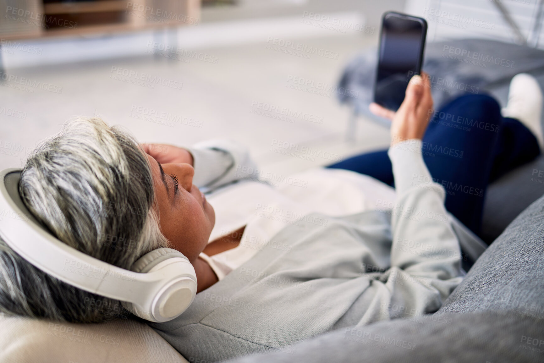 Buy stock photo Senior woman, headphones and phone on sofa, relax and music in home living room with search, choice and listening. Elderly lady, smartphone and audio streaming app for radio, podcast and lounge couch