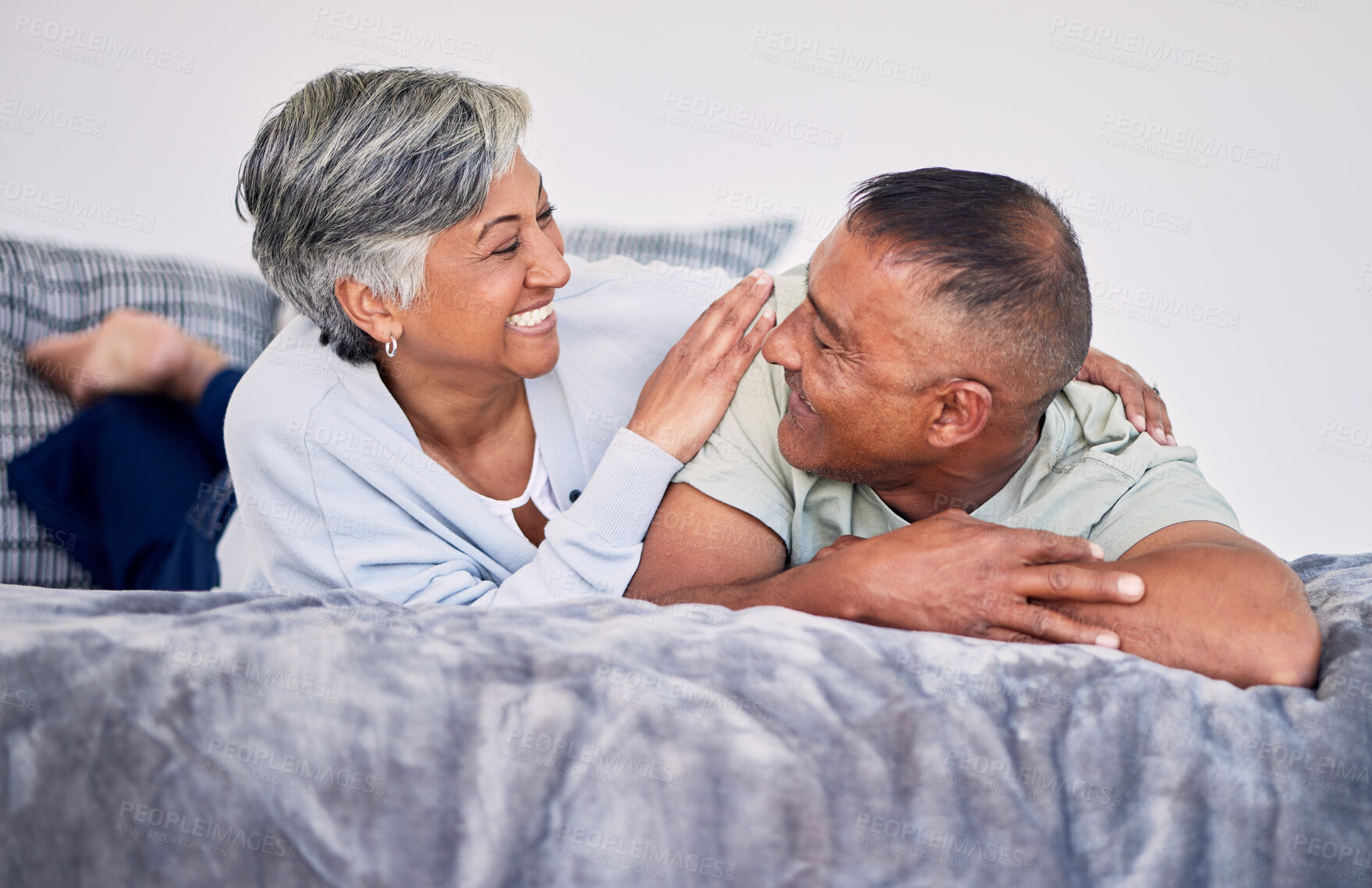 Buy stock photo Love, conversation and mature couple on their bed while relaxing, bonding and spending time together. Happy, smile and senior man and woman in retirement resting, talking and lying in bedroom at home