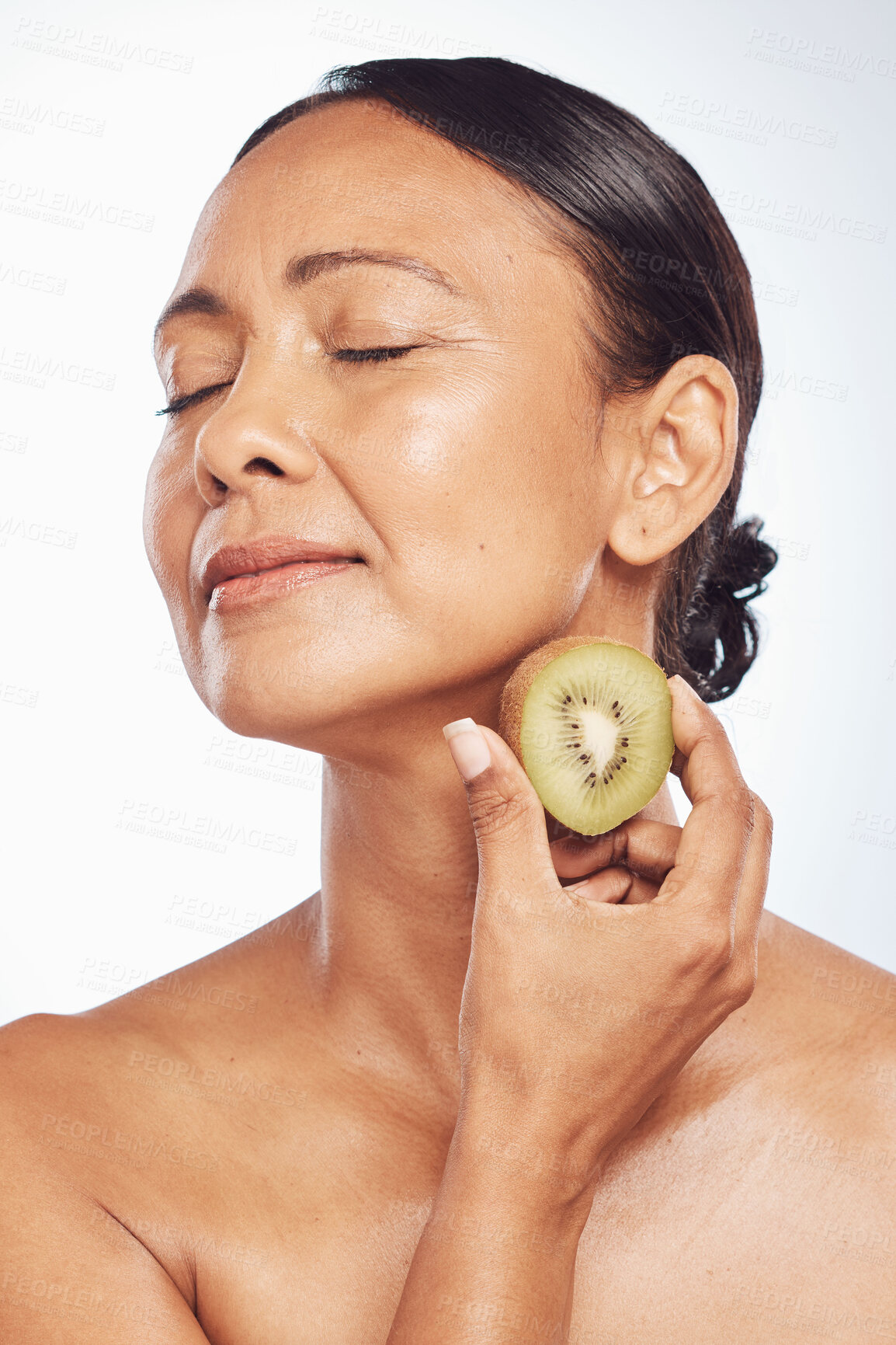 Buy stock photo Relax, beauty or mature woman with kiwi for healthy detox, skincare or facial treatment routine in studio. Spa, face or senior model with wellness, self love or fruit isolated on white background