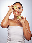 Skincare, portrait and senior woman with kiwi in studio isolated on a white background. Food, natural fruit and face of happy model with nutrition for wellness, healthy diet and anti aging for beauty