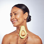 Skincare, thinking and senior woman with avocado in studio isolated on a white background. Happy, natural fruit and mature model holding food for nutrition, healthy diet or omega 3 for anti aging.