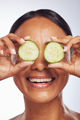 Buy stock photo Cucumber, face and skincare of happy woman in studio, white background and aesthetic shine. Female model, natural beauty and fruits on eyes for sustainable cosmetics, vegan dermatology and nutrition