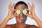 Face, cucumber and mask with a model woman in studio on a gray background for an antiaging facial treatment. Eyes, skincare and fruit with a young female person using cosmetic lay on her face