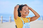 Face, smile and hair with a black woman on a blurred background by the ocean during summer vacation. Eyes closed, happy and braids with a young female person outdoor on the promenade for a holiday