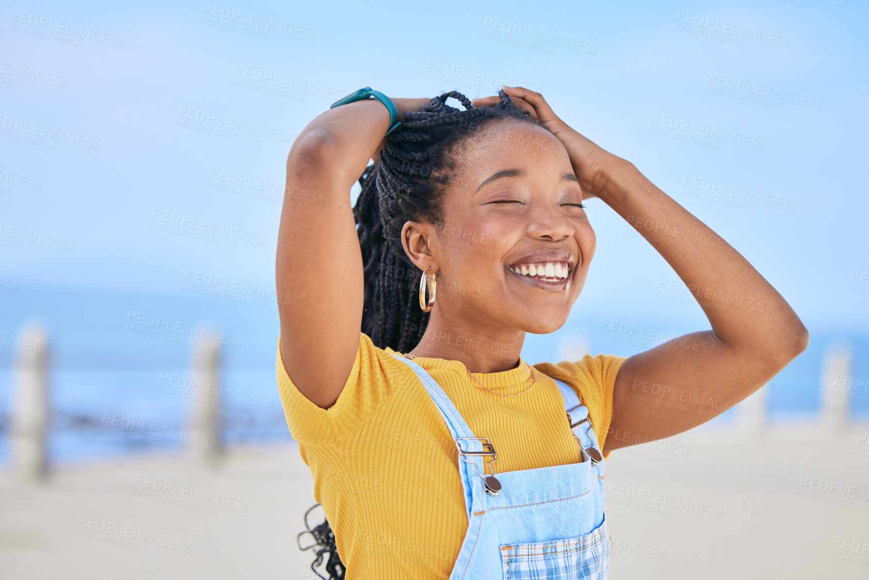 Buy stock photo Face, smile and hair with a black woman on a blurred background by the ocean during summer vacation. Eyes closed, happy and braids with a young female person outdoor on the promenade for a holiday