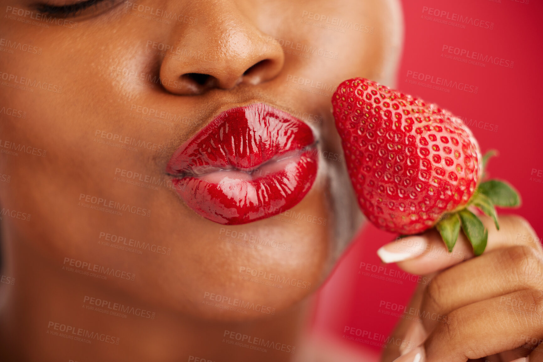 Buy stock photo Kiss, beauty and woman with strawberry on face with skincare or lips in red background or closeup. Cosmetics, wellness and nutrition with female or fruit in studio for detox and diet or self love.