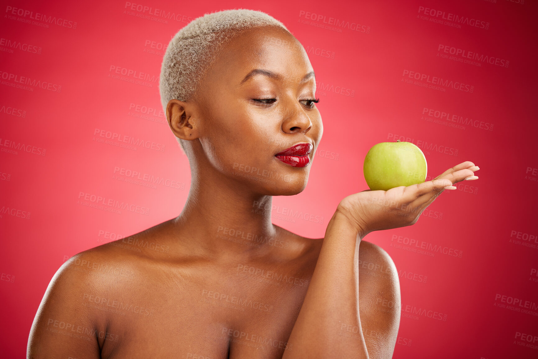 Buy stock photo Black woman, apple and thinking for natural nutrition or healthy diet against a red studio background. African female person palm with natural organic green fruit for food snack, health and wellness