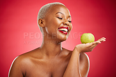 Buy stock photo Happy black woman, apple and natural nutrition for diet, health and wellness against a red studio background. African female person smile and palm with organic green fruit for food, snack or meal