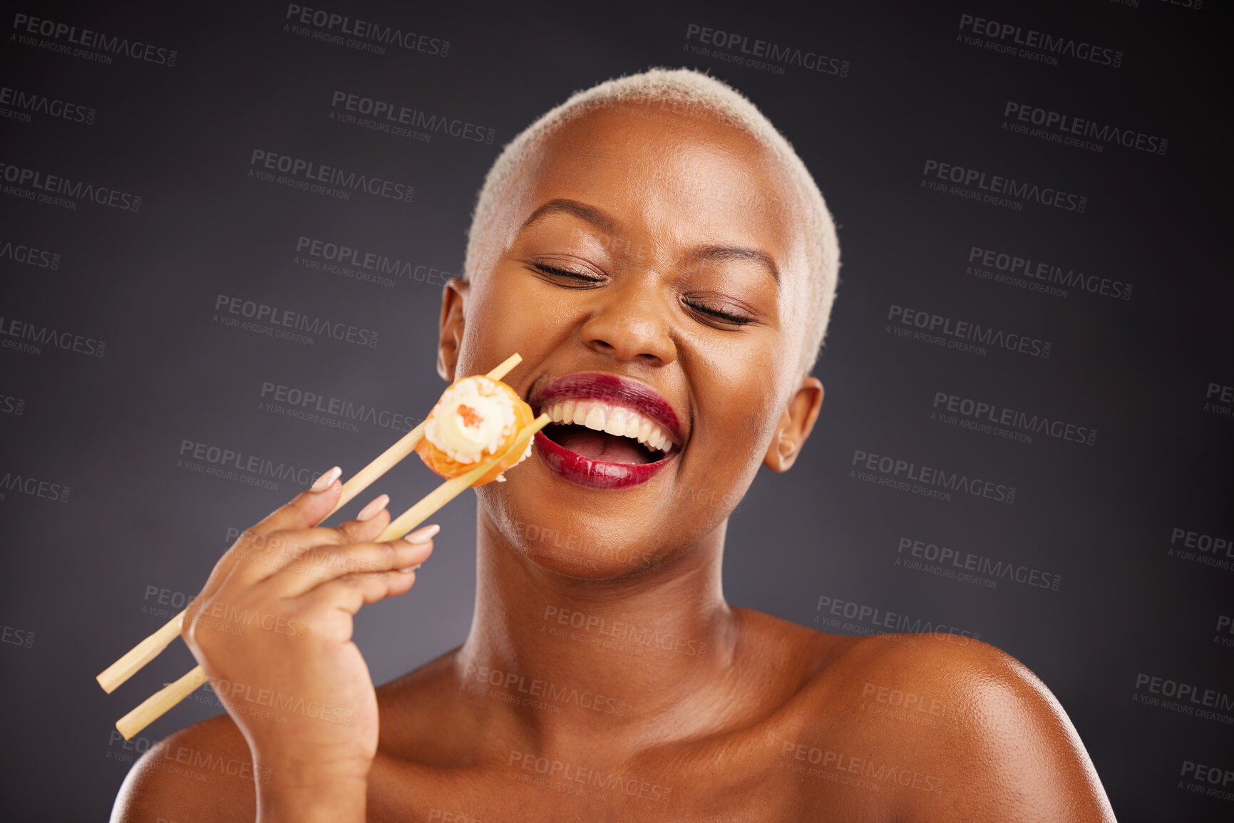 Buy stock photo Face, laugh and woman with sushi and chopsticks in studio for healthy eating, beauty or food. Black female model with makeup on a dark background for wellness glow, diet nutrition or funny seafood
