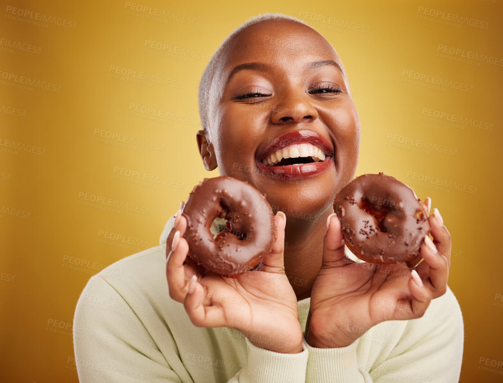 Buy stock photo Portrait, food and donut with a black woman in studio on a gold background for candy or unhealthy eating. Smile, chocolate and baking with a happy young female person holding sweet pastry for dessert