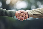 Shaking hands, senior man and people together in partnership, greeting or welcome with trust, bonding or moment in nature on blurred background. Handshake, support and solidarity with a person