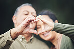Heart, hands and a senior couple in a house for love, care and showing an emoji together. Happy, trust and an elderly man and woman with a gesture for romance, marriage or valentines day with bokeh
