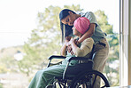Senior mother, woman and hug with wheelchair, love and care with bonding, kindness and nursing home. Girl, embrace and elderly person with disability for support, empathy or trust by window at clinic