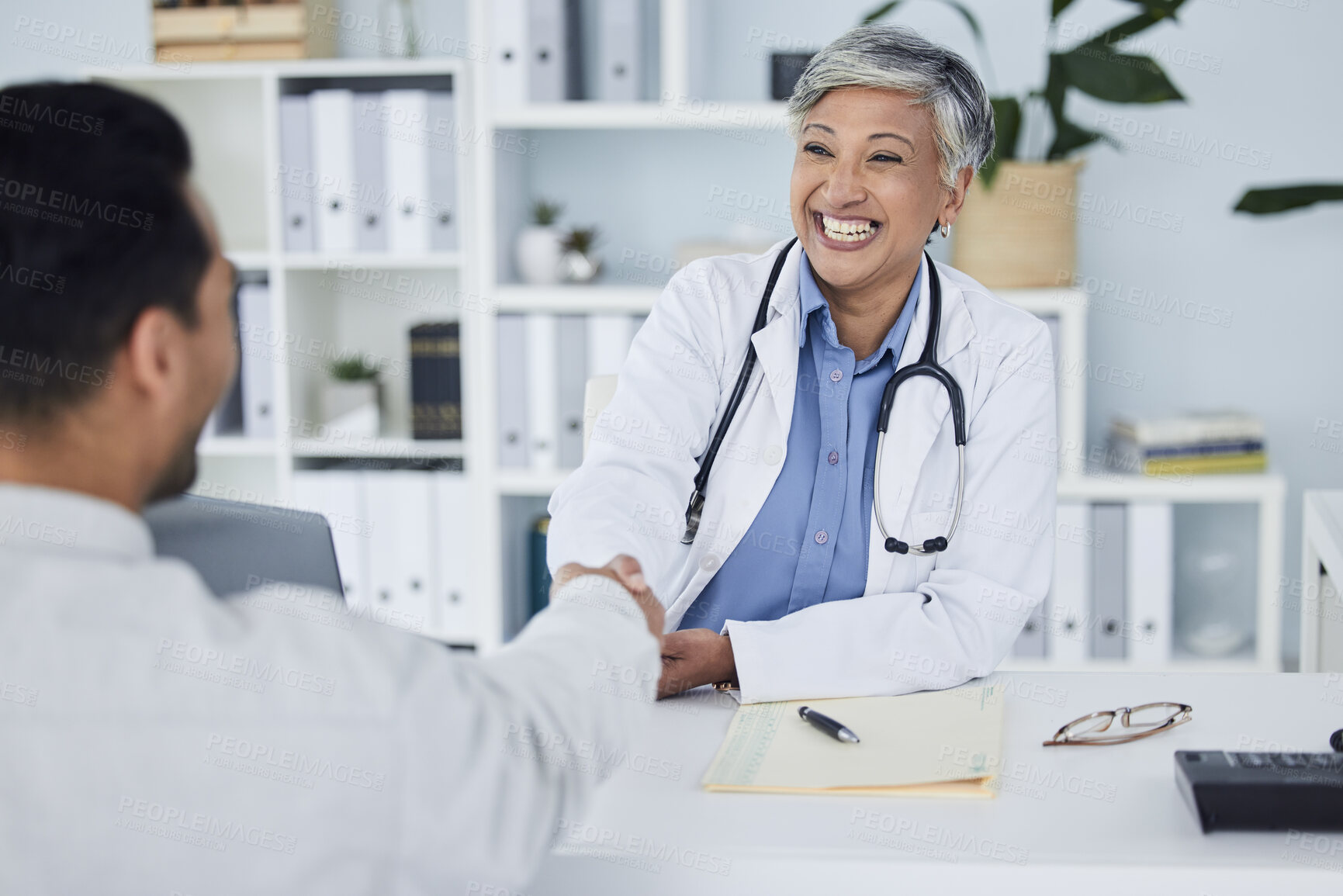 Buy stock photo Happy woman, doctor and handshake for meeting, hiring or partnership in consultation at the hospital. Senior female person, medical or healthcare professional shaking hands in interview or recruiting