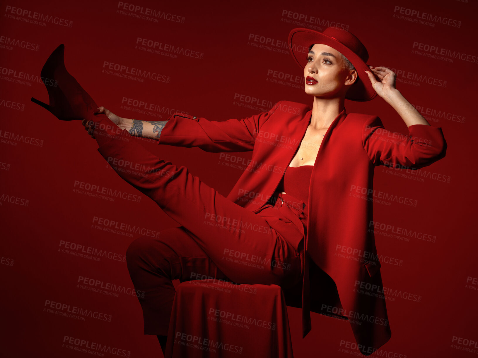 Buy stock photo Vision, fashion and a woman on a chair in studio on a red background for elegant or trendy style. Thinking, art and beauty with a young female person sitting in an edgy, classy or unique suit