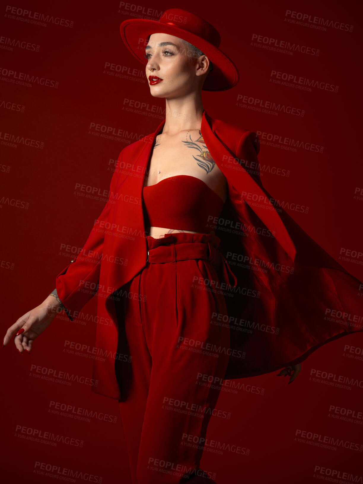 Buy stock photo Runway, fashion and a model woman on a red studio background for elegant art or trendy style. Aesthetic, beauty and wind with a young female person looking edgy, classy or unique in a clothes suit
