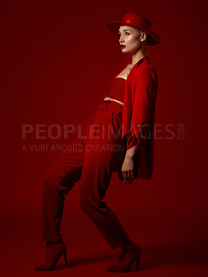 Buy stock photo Luxury, fashion and a woman runway model on a red studio background for elegant or trendy style. Aesthetic, art and confident with a young female person walking in an edgy or classy suit for beauty
