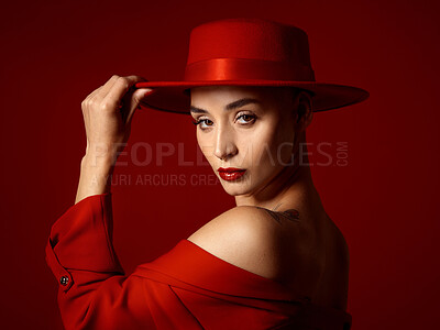 Buy stock photo Portrait, fashion and a confident woman on a red studio background for elegant or trendy style. Face, aesthetic and hat with a young female model in an edgy or classy outfit for aesthetic beauty
