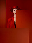 Portrait, fashion and mock up with a woman on a red studio background for marketing, advertising or branding. Luxury, aesthetic style and hat with a young female model standing with empty space