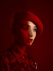 Woman, fashion and face with red aesthetic, beauty and makeup with vintage hat isolated on studio background. Retro style, female model with serious expression and cosmetics, attractive and bold