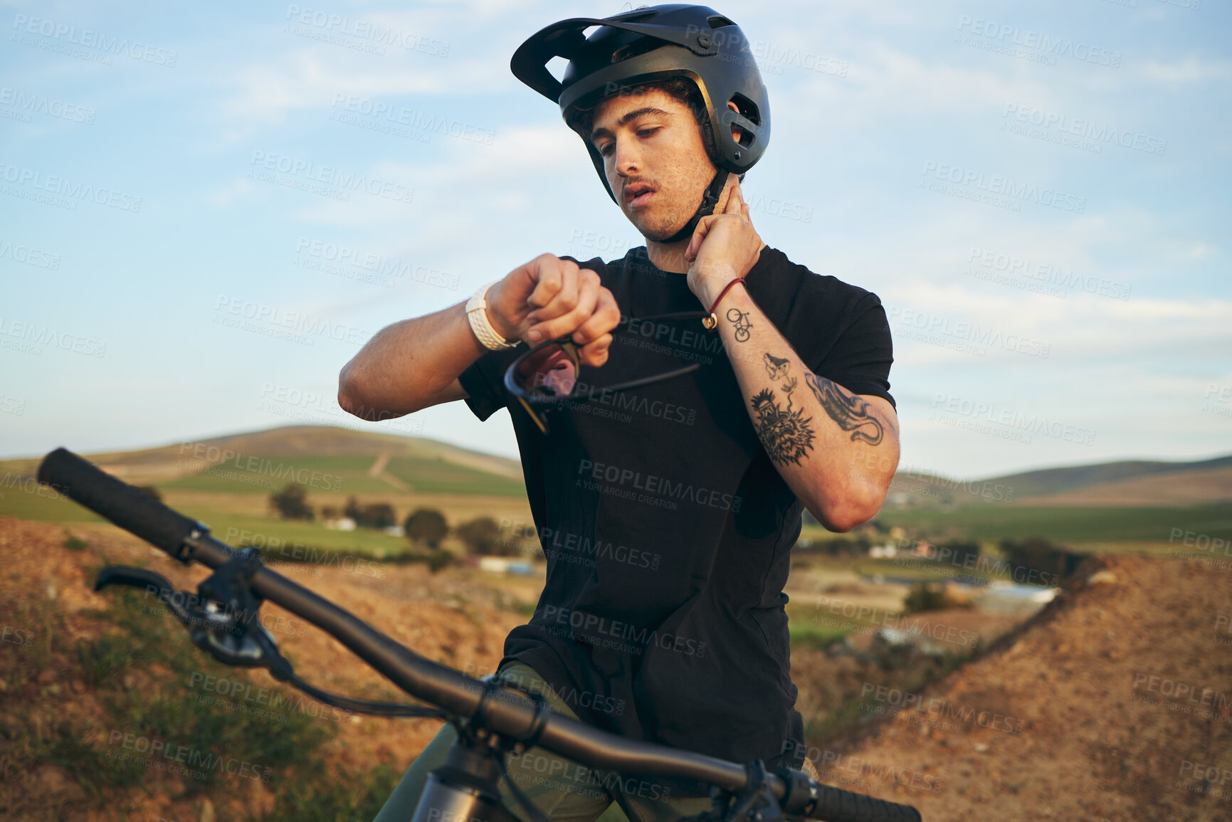 Buy stock photo Sports, bike and man checking his pulse on a mountain dirt road in nature for race or competition training. Fitness, exercise and young male biker athlete with watch for the time at an outdoor trail.