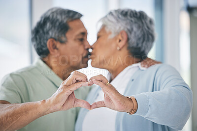 Buy stock photo Heart hands, mature couple and kiss with love, kindness and commitment to partner at home. Man, woman and finger shape for sign of support, trust and care of icon of emoji, loyalty and retirement