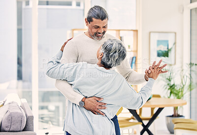 Buy stock photo Senior couple, hug and holding hands in dancing for love, care or bonding together in living room at home. Happy elderly man and woman enjoying quality time, retirement or celebration for anniversary