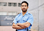 Portrait, man and security guard with arms crossed for police service, protection and safety in city. Law enforcement, bodyguard and serious asian male officer in blue uniform outdoor for town patrol