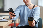 Young woman using smartphone texting holding cup of coffee relaxing in office