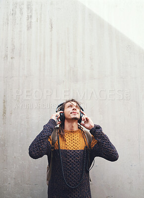 Buy stock photo Man is listening to music, student with headphones on university campus and future mindset against wall background. Gen z, education and male person at college, mockup space and podcast streaming