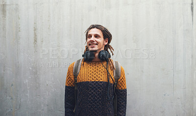 Buy stock photo Student, fashion and gen z male with music headphones outdoors, happy and in stylish clothes on wall background. Travel, freedom and guy smile downtown with contemporary, outfit and podcast earphones