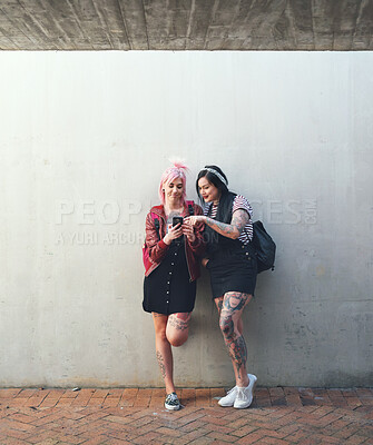 Buy stock photo Friends, smartphone and students, women against wall background with social media and check chat online. Young female people on college campus, using phone and app, punk fashion and communication