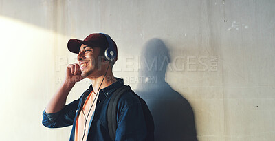 Buy stock photo Happy man, student and headphones, listening to music on campus with happiness and audio against wall background. Gen z, education and male person at college, mockup space and podcast streaming