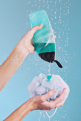 Buy stock photo Woman, hands and loofah with soap in shower for hygiene, washing or cleaning body against a blue studio background. Closeup of female person pouring gel bottle with falling water or rain on sponge