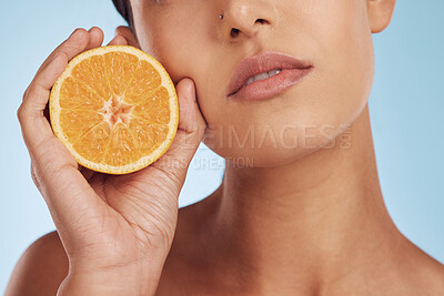 Buy stock photo Woman, hands and orange for vitamin C, skincare or diet against a blue studio background. Closeup of female person holding organic citrus fruit for natural nutrition, dermatology or healthy wellness