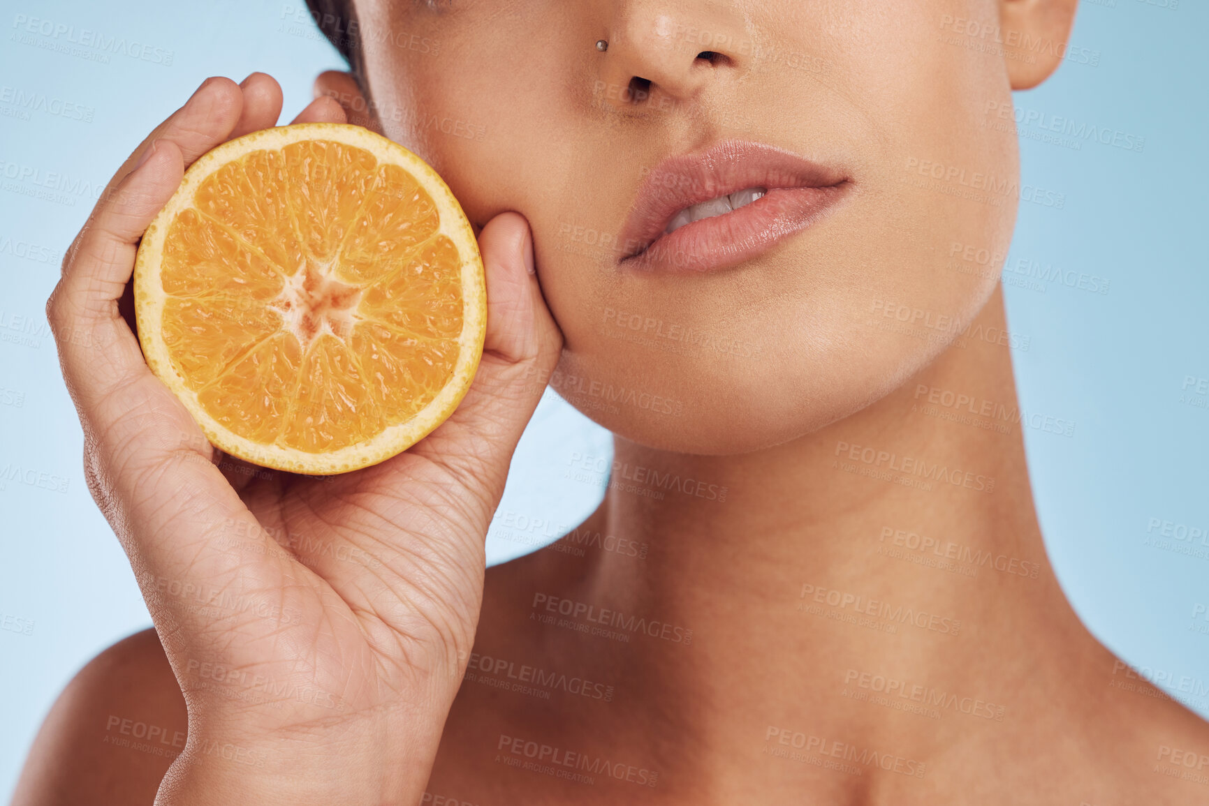 Buy stock photo Woman, hands and orange for vitamin C, skincare or diet against a blue studio background. Closeup of female person holding organic citrus fruit for natural nutrition, dermatology or healthy wellness